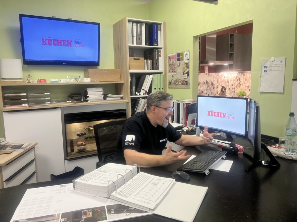 Küchenstudio für Freital, Radebeul, Meißen und das Dresdner Umland 10 Planungsplatz im Studio mit zwei Bildschirmen und aufgeschlagenen Planungsunterlagen